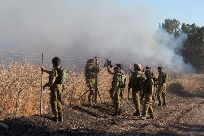Israeli soldiers stand next to smoke from a fire caused by a rocket attack. Rockets that struck an northern Israeli village near the Lebanese border, causing no casualties, were launched from the Syrian Golan Heights, Israeli soldiers