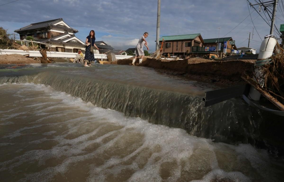 Residents cross an area still flooded in Kurashiki, Okayama prefecture Japan floods