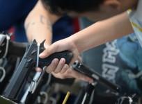 Visitors examine handguns for sale during the opening of the annual gun show in Manila