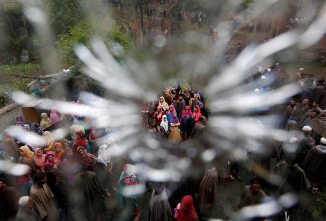 People are seen through a bullet hole in a window of a damaged house after a gun battle between suspected militants and Indian security forces at Turkewangam village in Kashmir's Shopian district, May 3, 2018. Gun battle in Kashmir