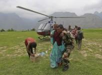 A woman is assisted by a soldier as she leaves an army helicopter during a rescue operation at Joshimath in the Himalayan state of Uttarakhand
