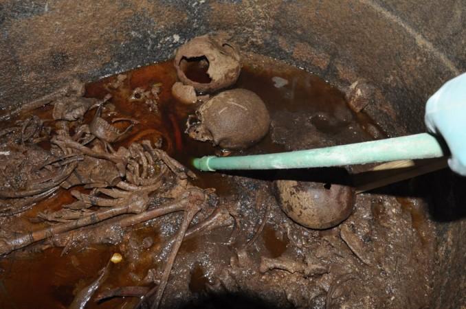 A handout picture released on July 19, 2018 by the Egyptian Antiques ministry shows skeletons in the black granite sarcophagus uncovered early this month in the Sidi Gaber district of Alexandria, filled with sewage water. - Skeletons are believed to be three warriors as one of the skulls bear a wound resulted from the hit of an arrow Alexandrian sarcophagus