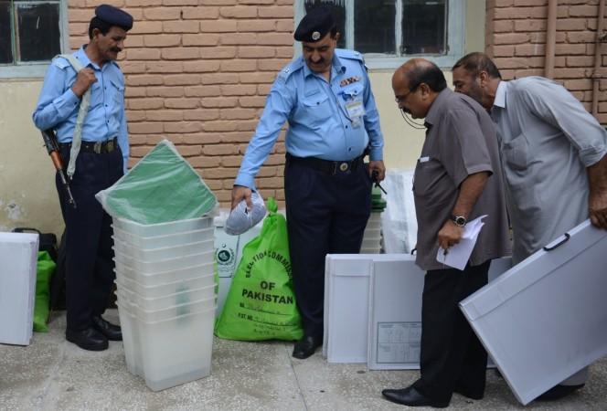 Pakistani police stand guard as election officials look at election materials at a distribution centre in Islamabad on July 24, 2018 Pakistan poll
