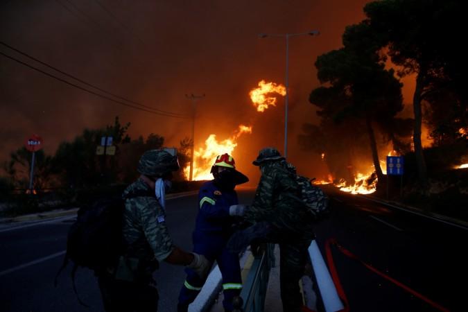 Firefighters and soldiers fall back as a wildfire burns in the town of Rafina, near Athens, Greece wildfire
