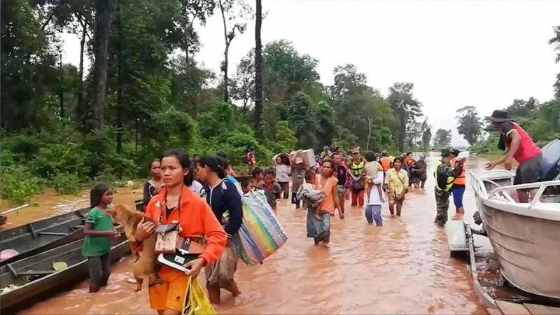 People walk through flooded area after being brought to safety by boat in Sanam Xay district, Attapeu Province, Laos after a hydropower dam under construction in Southern Laos collapsed, in this still picture taken from social media video obtained July 24, 2018. People walk through flooded area after being brought to safety