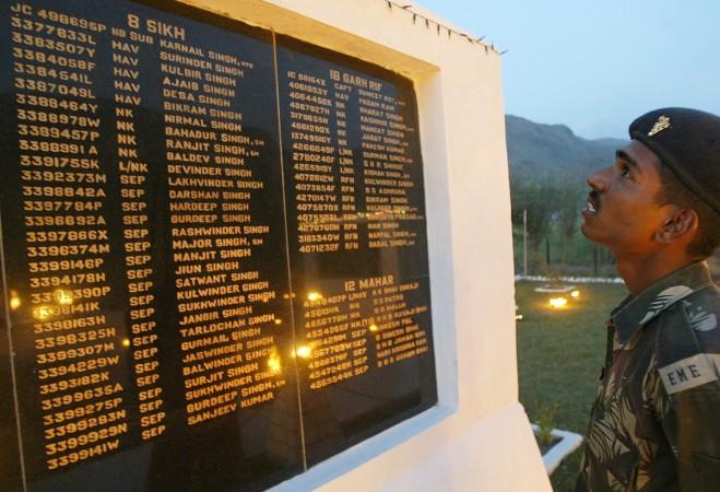 An Indian army soldier looks at the names of fallen colleagues at a war memorial during Vijay Diwas Kargil Vijay Diwas