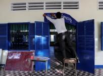 An election worker hangs a banner outside a classroom at a school in Phnom Penh