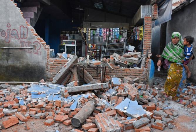 A woman walks past debris from a collapsed wall following a strong earthquake in Lendang Bajur Hamlet, Lombok island, Indonesia Indonesia earthquake