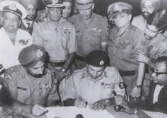 In picture: Lt Gen Niazi signs the Instrument of Surrender under the gaze of Lt Gen Aurora, essentially declaring independence for Bangladesh. Standing immediately behind from L to R: Vice Admiral Krishnan, Air Marshal Dewan, Lt Gen Sagat Singh, Maj Gen JFR Jacob (with Flt Lt Krishnamurthy peering over his shoulder). Veteran newscaster Surojit Sen of All India Radio is seen holding a microphone on the right. Bangladesh Liberation War