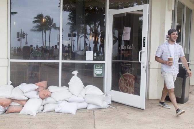 Tourist John Soltys leaves a Starbucks as sandbags line the windows in preparation for Hurricane Lane as it approaches Waikiki Beach on August 23, 2018 in Honolulu Hurricane Lane