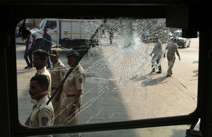 Indian policemen walk past the broken window of a bus after a Republican Party of India (RPI) protest turned violent in Mumbai on January 2, 2018. India's Republican Party supporters turn violent during a protest on January 2, a day after the death of young Dalit activist in Maharashtra's Pune district following an altercation between two groups during celebrations to mark the bicentenary of a British-Peshwa war Sudha Bharadwaj