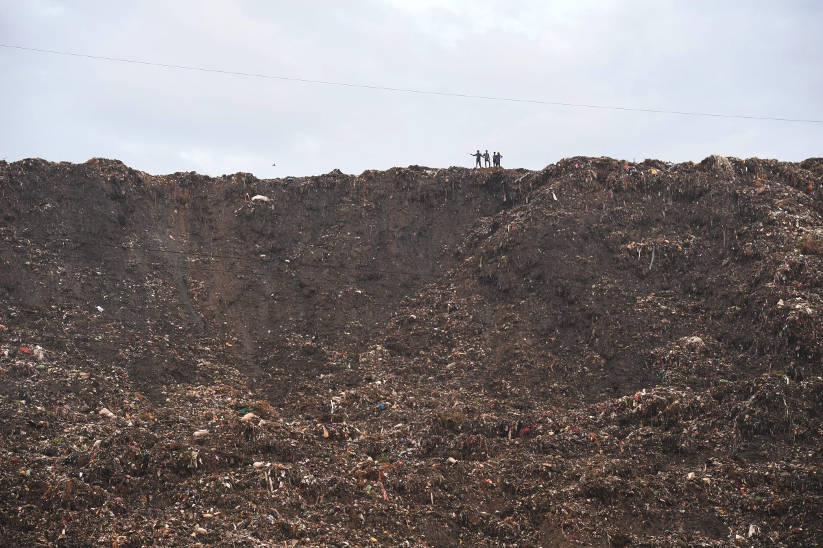 People stand atop a garbage landfill after a section collapsed in Ghazipur area in India's capital New Delhi on September 1, 2017. Rescue personnel recovered two bodies as rescue operations continue, local media reported. Ghazipur landfill