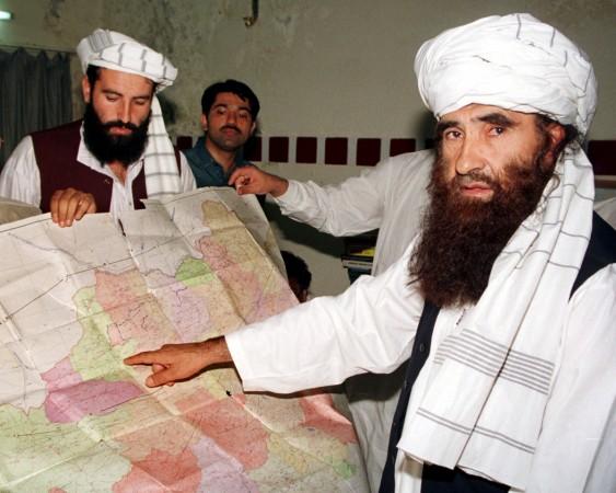 Jalaluddin Haqqani (R) points to a map of Afghanistan during a visit to Islamabad, Pakistan, October 19, 2001, as his son Naziruddin (L) looks on. Jalaluddin Haqqani