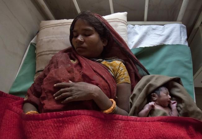A mother rests on a bed along with her newborn baby Pregnant mother