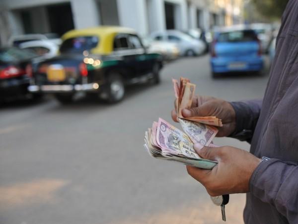 A parking lot employee counts Indian rupee notes in New Delhi on December 15, 2011. Indian rupee