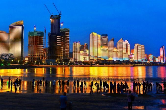 - This photo taken on May 26, 2018 shows residents and visitors looking at illuminated buildings in Qingdao in China's eastern Shandong province. - This year's summit of Shanghai Cooperation Organization (SCO) will be held in the city of Qingdao in June. china skyline skyscrapers buildings