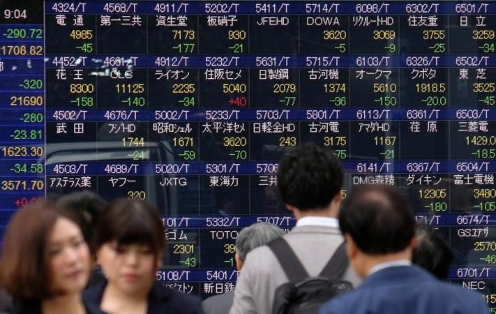 Pedestrians walk past a stock indicator board of the Tokyo Stock Exchange in Tokyo on December 5, 2018. - Tokyo stocks opened lower on December 5, following a plunge on Wall Street on worries about US economic growth and with investors cautious ahead of key US jobs data. (Photo by Kazuhiro NOGI / AFP) JAPAN-STOCKS