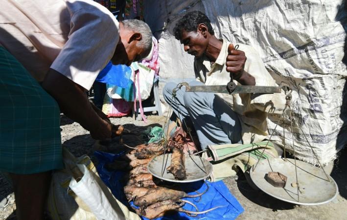An Indian Tea-tribe vendor sells cooked rats at a weekly market in Kumarikata village along the Indo-Bhutan border, some 90km from Guwahati, on December 23, 2018. - Vendors sell rat meat at around Rs 200 per kg. (Photo by Biju BORO / AFP) An Indian Tea-tribe vendor sells cooked rats at a weekly market in Kumarikata village along the Indo-Bhutan border