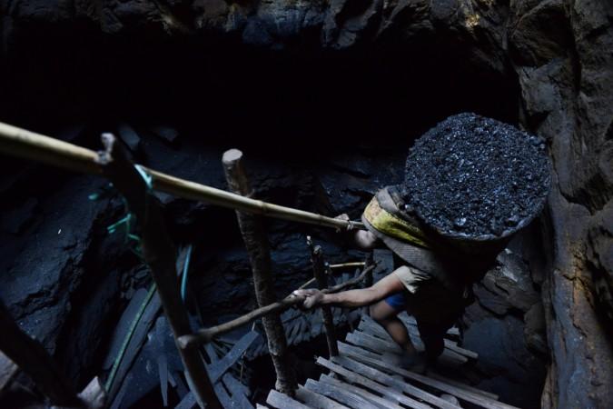 A miner slowly carries a heavy load of wet coal on a basket hundreds of feet up on wooden slats that brace the sides of a deep coal mine shaft in Meghalaya. Meghalaya Coal mine