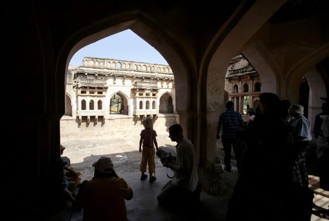 Tourists stands inside queen of the Vijaynagara empire's swimming pool in Hampi, near the southern Indian city of Hospet, some 360 Kms north of Bangalore on April 11, 2008. Hampi is located within the ruins of the city of Vijayanagar, the former capital of the Vijayangar empire. The village of Hampi, which is a UNESCO world heritage site, contains several other monuments belonging to the old city. hampi