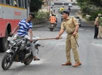 A police personnel canes a motorcyclist during a curfew following violence in the city due to the Cauvery water sharing dispute with neighbouring state Tamil Nadu, in Bangalore on September 13, 2016