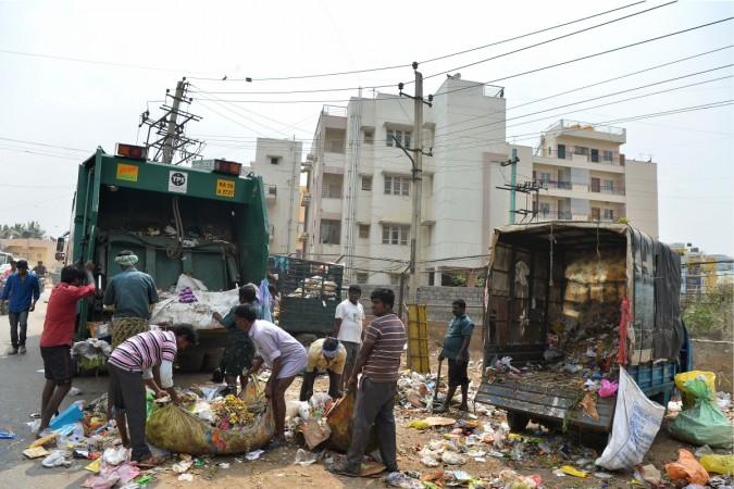 This photo taken on January 11, 2017 shows municipality workers of the Bruhat Bengaluru Mahanagara Palike (BBMP) loading garbage onto a truck in a residential area in Bangalore. The surge in Bangalore's population since the start of the 1990s has placed huge pressure on its municipality, which stands accused of inadequate urban planning and, in particular, of failing to cope with the accompanying rise in waste volumes. / AFP / Manjunath KIRAN / TO GO WITH India-environment-waste-social,FEATURE by Alexandre MARCHAND Bruhat Bengaluru Mahanagara Palike