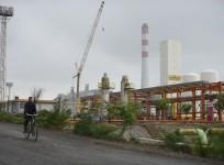 a worker cycling by an Indian oil refinery