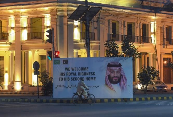 A Pakistani man rides past a billboard displaying a portrait of Saudi Arabian Crown Prince Mohammed bin Salman, ahead of the prince's arrival, in Lahore Prince Salman pakistan visit