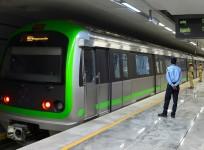 Security personnel watch the trial run of a train running on the yet to be inaugurated Green Line of the Namma Metro Rail at Majestic Station