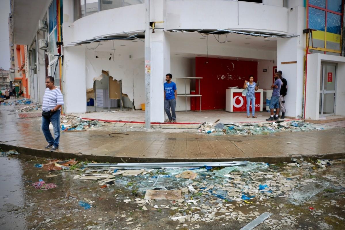 Residents and shopkeeper are seen amid the destruction provoked by the passage of the cyclone Idai in Beira, Mozambique, on March 17, 2019 Mozambique
