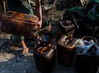a worker filling containers with crude oil at an informal oil field in Minhla township, central Myanmar