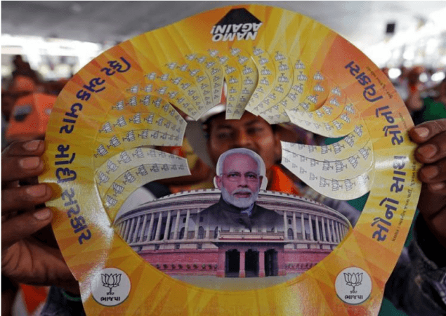 A supporter of Prime Minister Narendra Modi displays a paper cap with images of Modi and Indian Parliament during an election campaign rally in Junagadh, Gujarat. Narendra Modi
