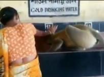 A woman helps thirsty monkey drink water at a railway station