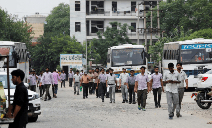 Labourers walk along a street next to a Maruti Suzuki India Ltd manufacturing plant in Manesar in the northern state of Haryana. Maruti Suzuki