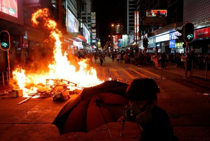 An anti-extradition bill protester holds an umbrella in front of a burning barricade during a protest at Mong Kak in Hong Kong on September 6, 2019. Hong Kong violence
