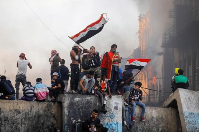 An Iraqi demonstrator carries the Iraqi flag during ongoing anti-government protests, in Baghdad, Iraq. Iraq protests