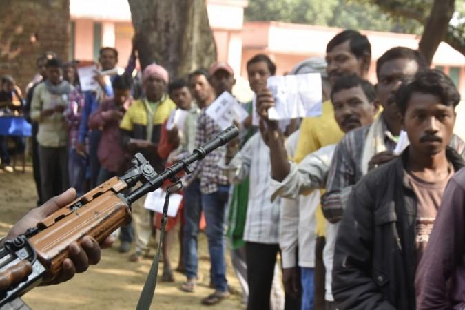 Voters standing in a queue show voter ID Cards during first phase of assembly election in Jharkhand. Jharkhand assembly elections
