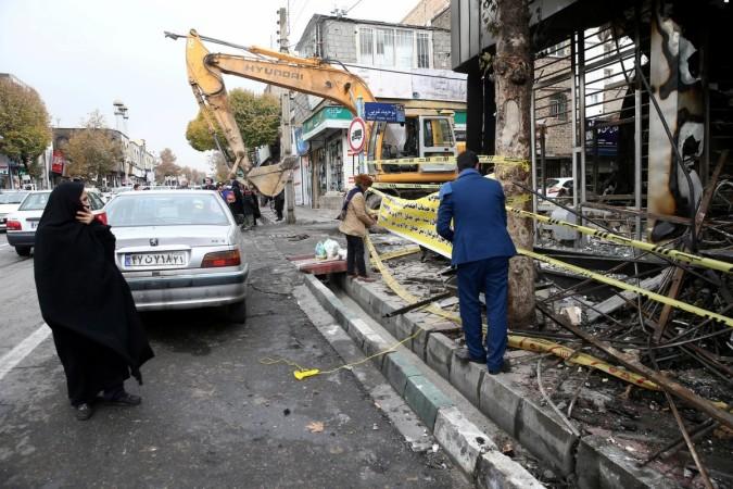 People walk near a burnt bank in Tehran. Iran protests