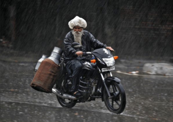 FILE PHOTO: A milkman rides a motorcycle during a heavy rain shower in the northern Indian city of Chandigarh July 2, 2014. REUTERS/Ajay Verma FILE PHOTO: A milkman rides a motorcycle during a heavy rain shower in the northern Indian city of Chandigarh July 2, 2014. REUTERS/Ajay Verma
