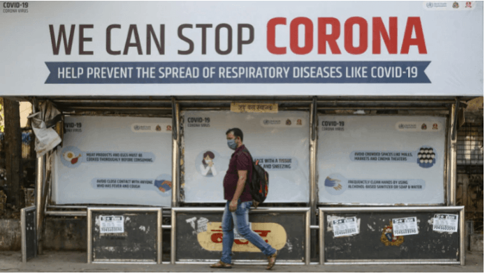 A man wearing a protective mask walks past a bus stop displaying preventive measures against the coronavirus in Mumbai. coronavirus in india