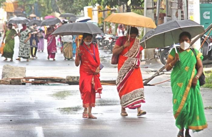 Bengaluru: People shield themselves using umbrellas during rains in Bengaluru on July 20, 2020. IANS Bengaluru: People shield themselves using umbrellas during rains in Bengaluru on July 20, 2020.