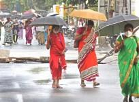 Bengaluru: People shield themselves using umbrellas during rains in Bengaluru on July 20, 2020.