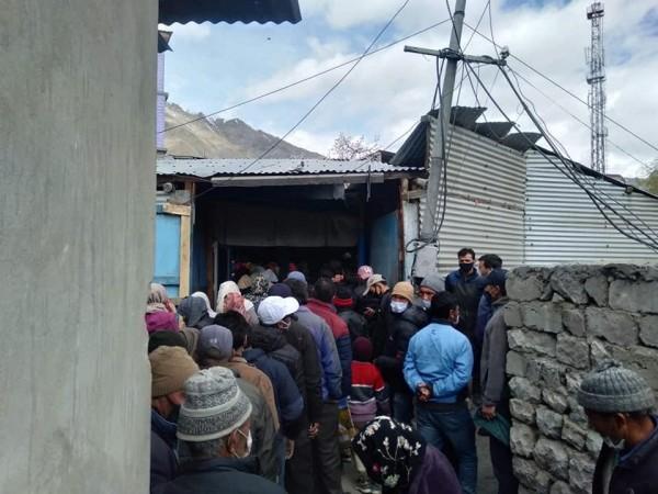 People rush to purchase fresh vegetables from a shop in Kargil