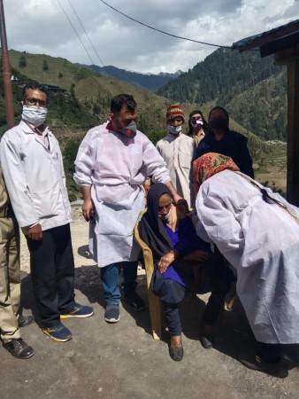 Health workers vaccinating 120-year-old Dholi Devi