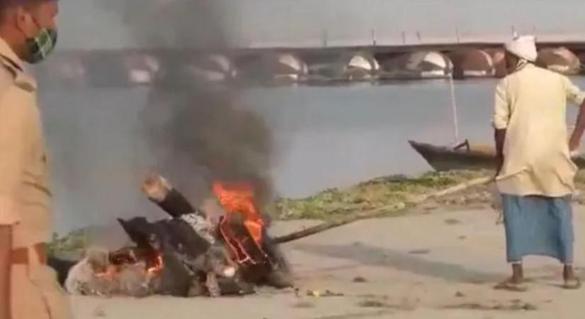 UP Police personnel oversees a pyre burning with the help of Petrol UP Police