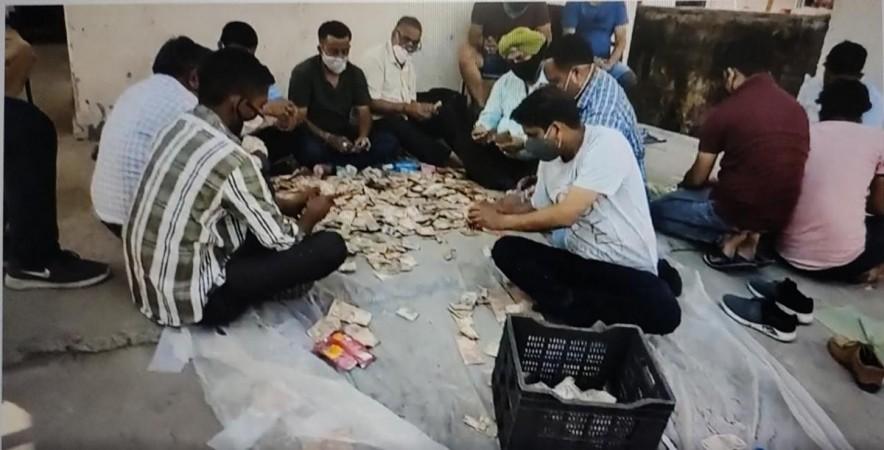 Locals counting money recovered from beggar's shanty Locals counting money recovered from beggar's shanty