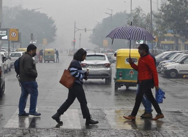 People hold umbrellas cross a path amid rain at Connaught Place in New Delhi (File Photo) People hold umbrellas cross a path amid rain at Connaught Place in New Delhi