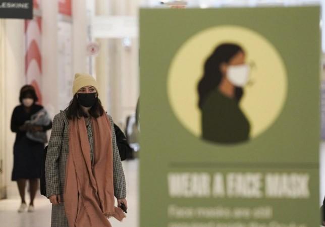 People walk past a signboard of wearing face masks at the Oculus of the World Trade Center in New York, the United States, March 29, 2022. People walk past a signboard of wearing face masks at the Oculus of the World Trade Center in New York, the United States, March 29, 2022.