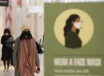 People walk past a signboard of wearing face masks at the Oculus of the World Trade Center in New York, the United States, March 29, 2022.