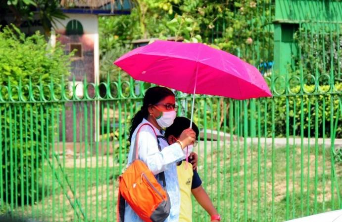 A woman uses an umbrella to protect from heat during a hot summer day in New Delhi on Sunday, Apr. 24, 2022